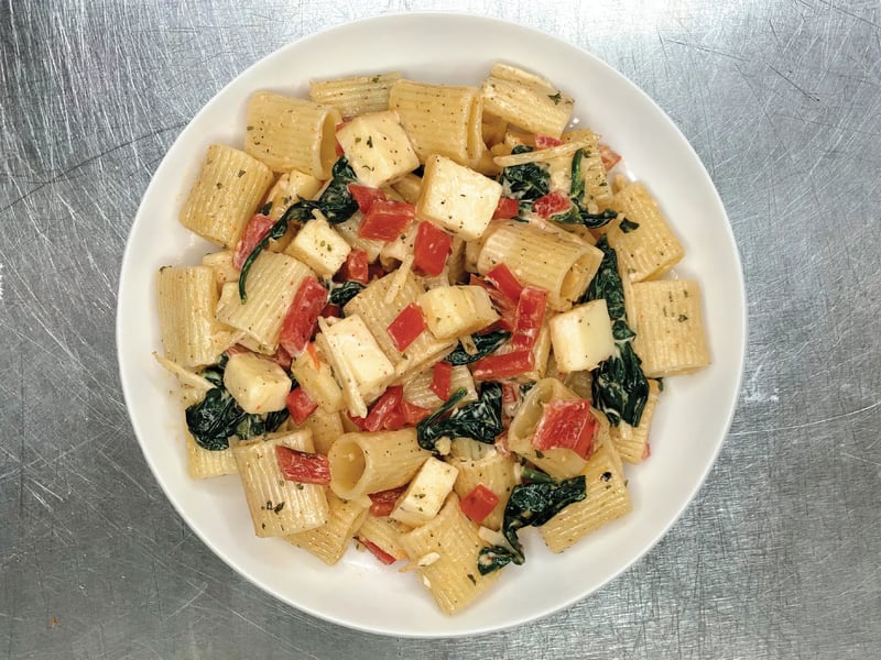 Bowl of rigatoni pasta salad with spinach, red peppers, and mozzarella