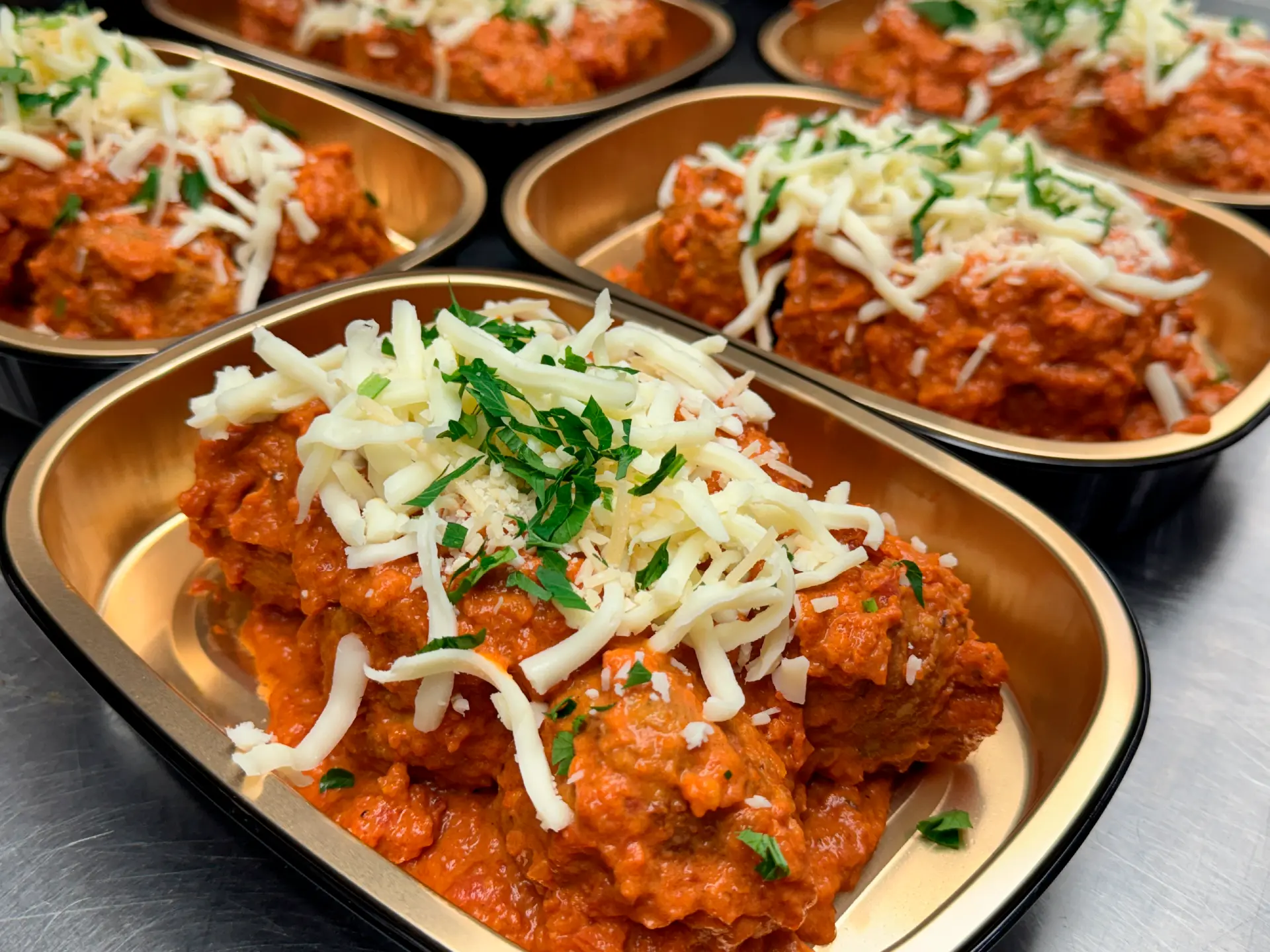 Heat and serve meatball trays topped with mozzarella and parsley