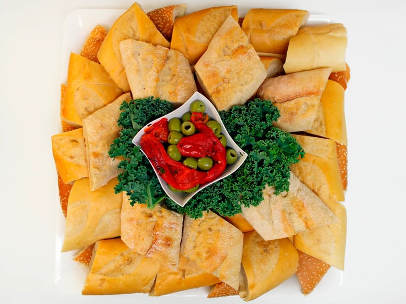 Tray of sliced Italian breads arranged around olives and kale