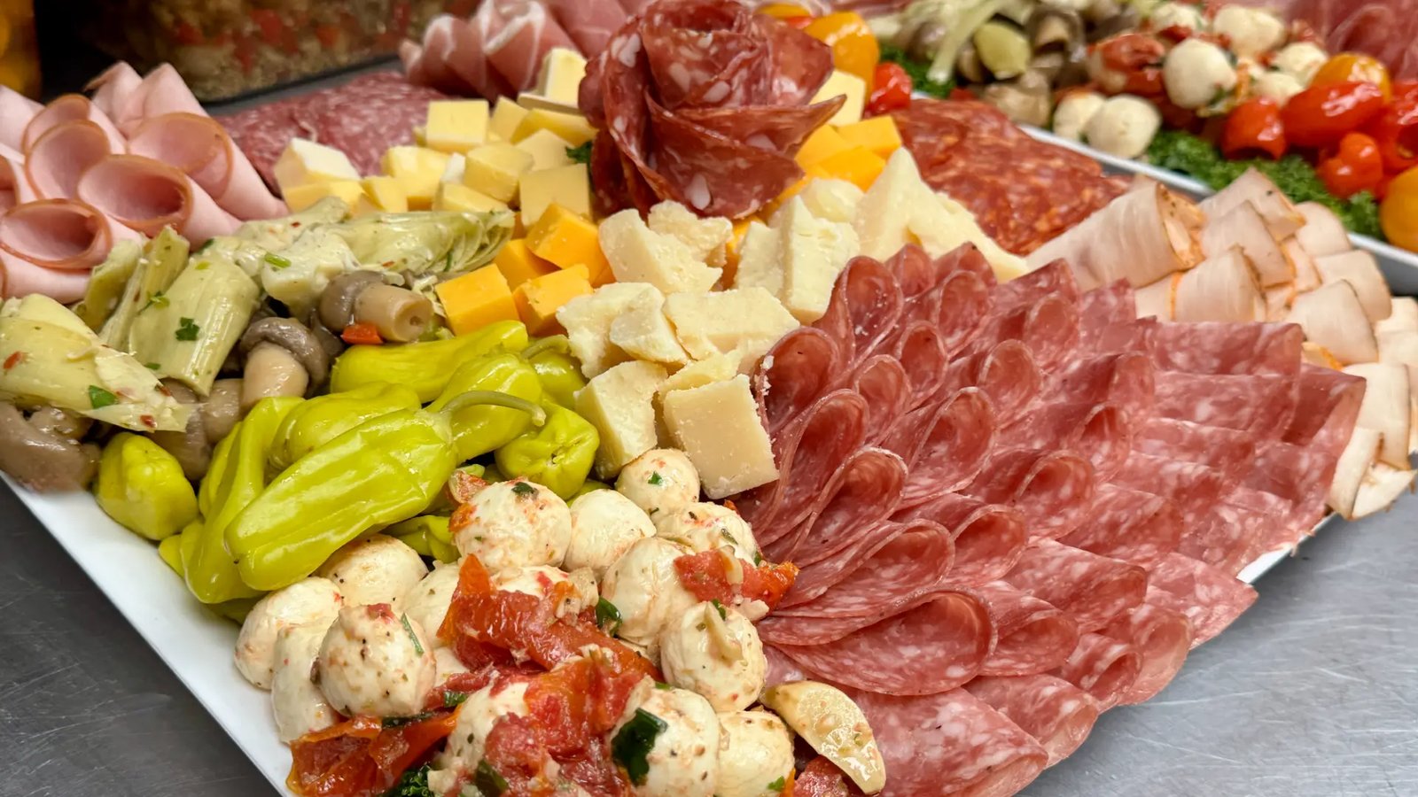 Sam's catering deli platter with sliced salami, cheeses, marinated vegetables, and mozzarella